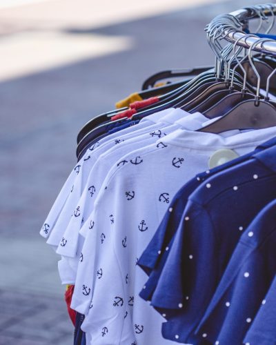 A selective focus shot of some colorful shirts on hangers on the sidewalk